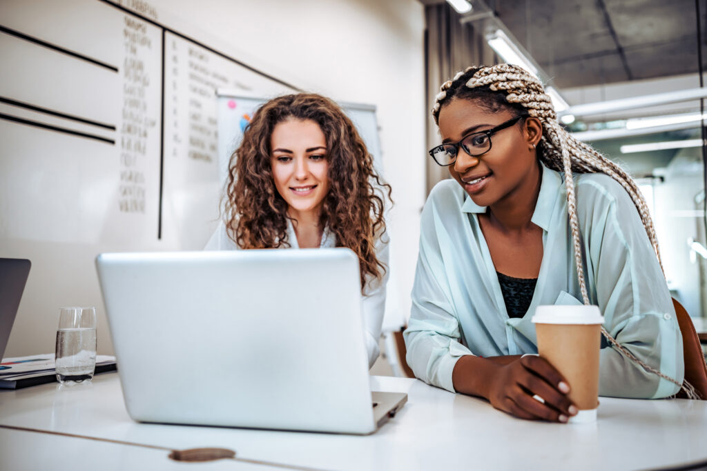 Two female coworkers collaborating on laptop