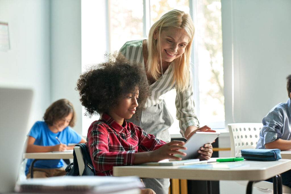 female teacher helping middle school girl with class work on a tablet