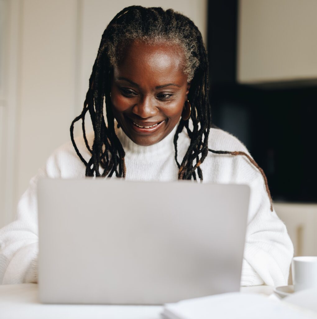 mature woman smiling happily while typing on a laptop at home