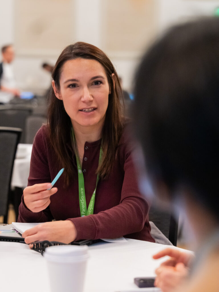 Female conference attendee engaged in conversation with colleague at table