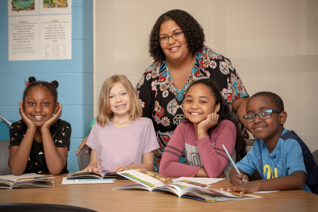 teacher with group of students|Hampton City Schools|Group of graduating students|Hampton City Schools Case Study PDF|Hampton City Schools Case Study