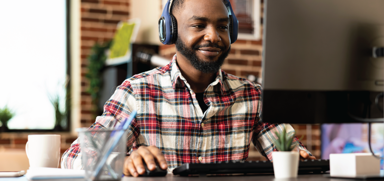 man wearing headphones working on desktop computer